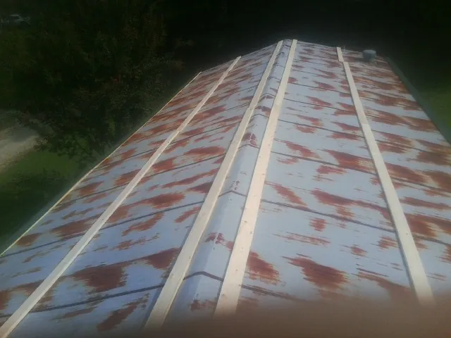 Rusted metal roof panels with new wood purlins before replacement — Storm Damage Roof Repair in West Farmington by Roofing Brothers