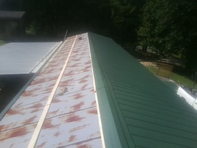 Old rusted panels beside newly installed green metal roofing — Wind Damage Roof Repair by Roofing Brothers in West Farmington
