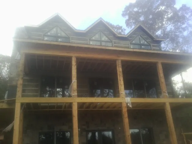 Dormers and porch framing on a large log home under construction — Roof Coating work by our crew in West Farmington