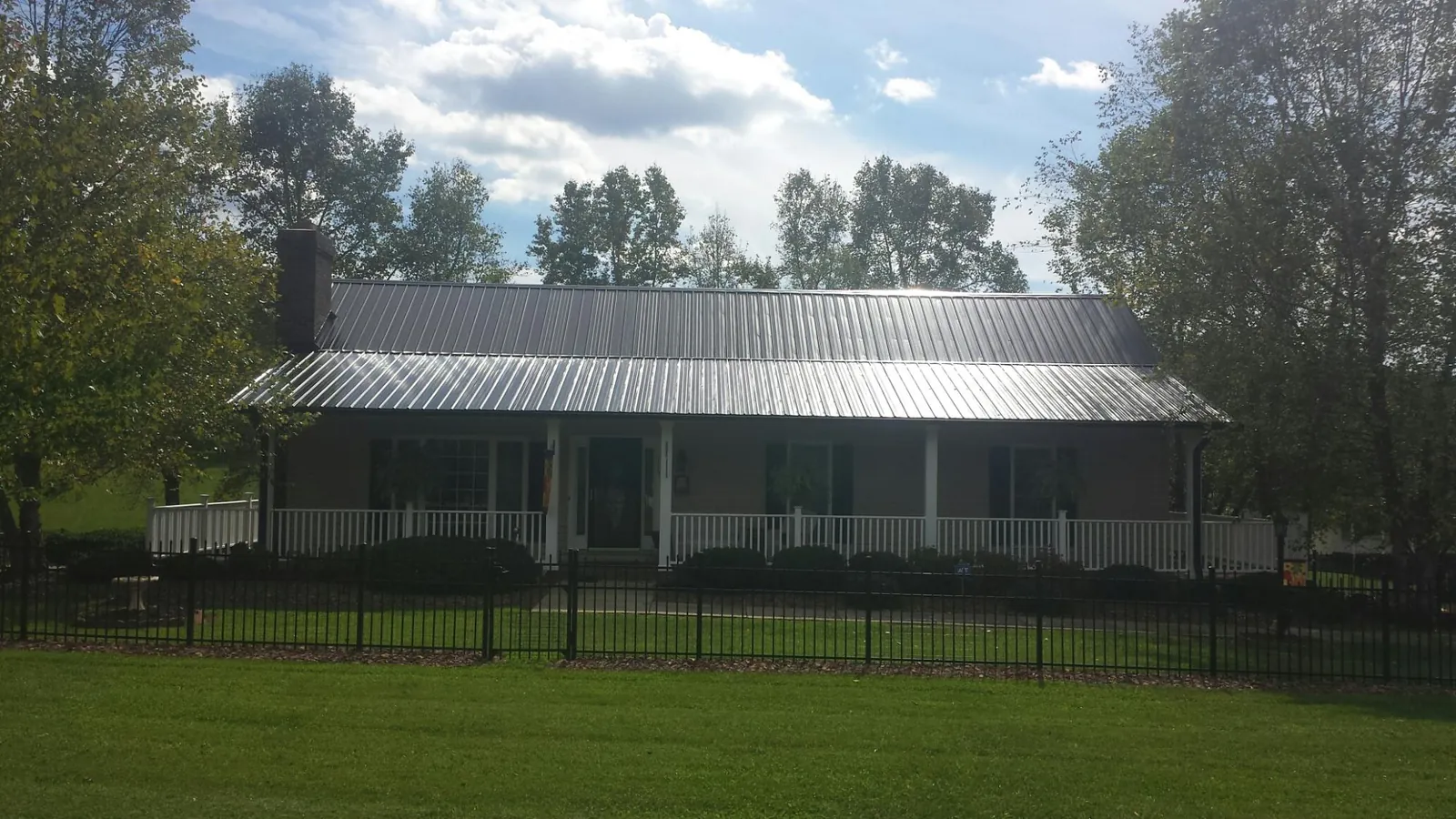 Gray metal roof on a brick ranch with a full width front porch — Gutter Guard Installation work by our crew in West Farmington