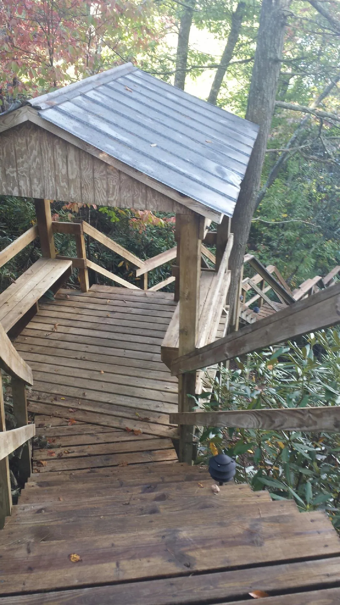 Metal roofed shelter over wooden steps on a wooded walkway — Skylight Repair & Installation work by our crew in West Farmington