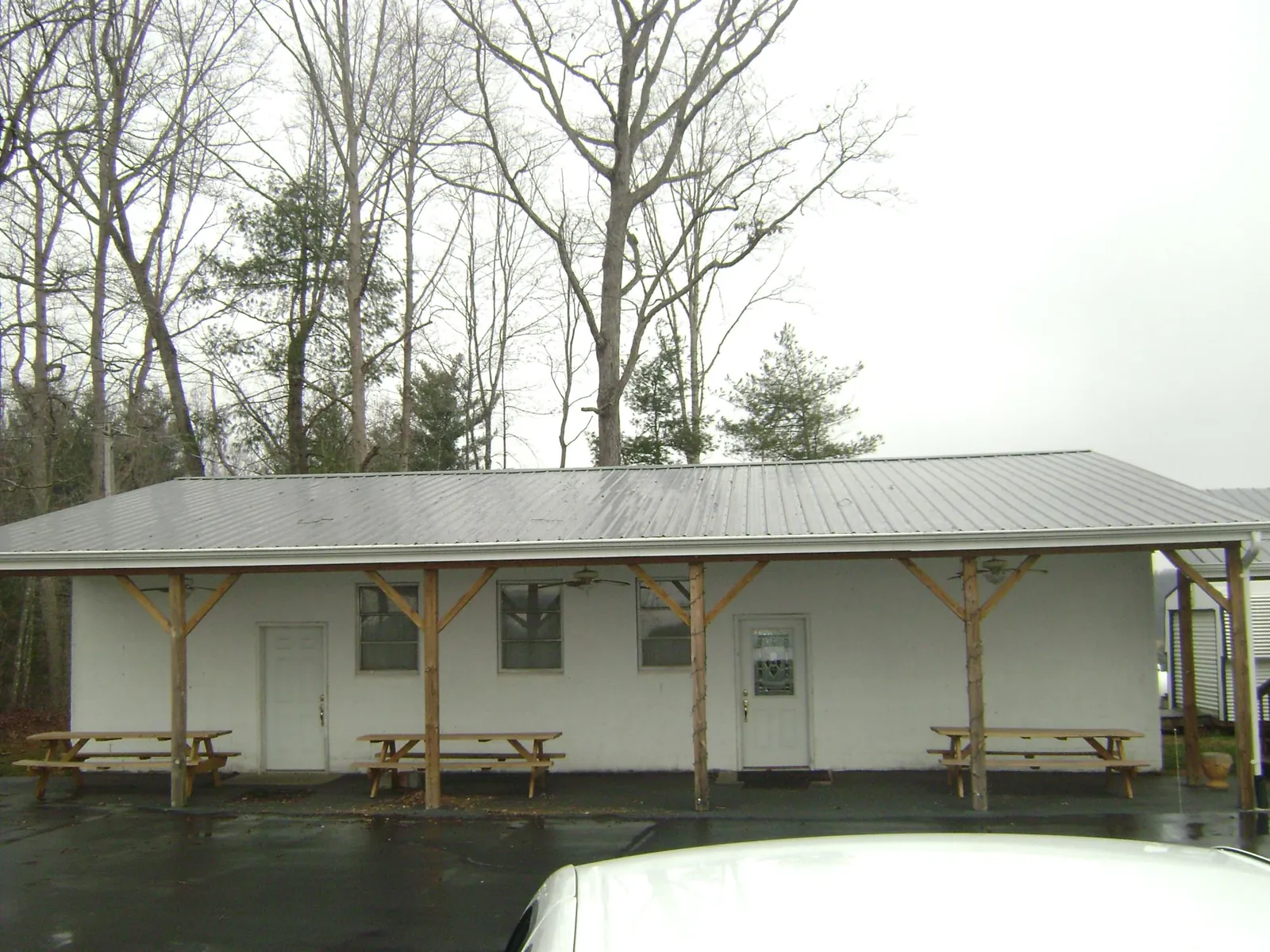 Gray metal roof over a block building with a timber post porch in West Farmington