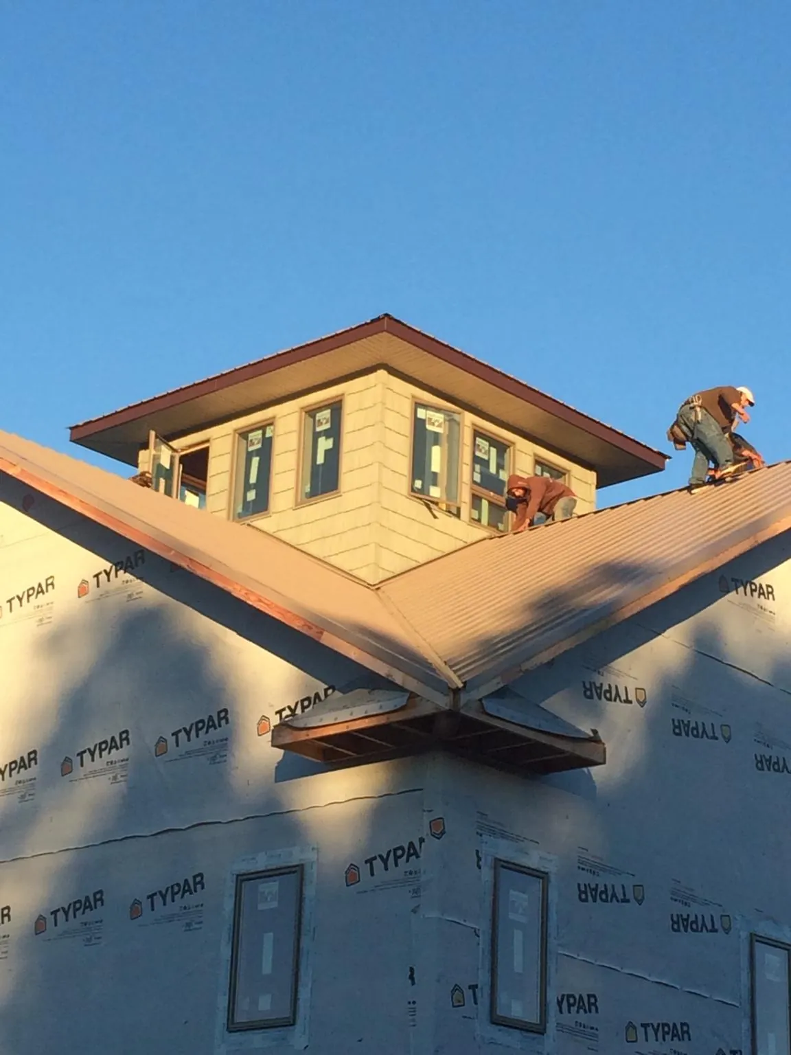 Roofers working around a rooftop cupola on a new metal roof at sunset — Roof Waterproofing in West Farmington by Roofing Brothers